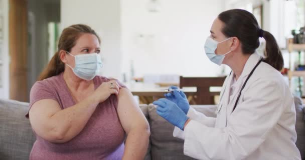 Vit Kvinna Och Kvinnlig Läkare Med Ansiktsmasker Vaccinerande Hushållsliv Att — Stockvideo