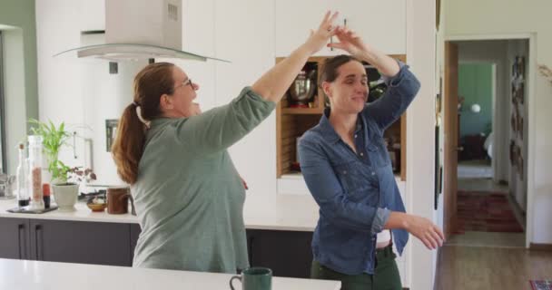 白人レズビアンのカップルはキッチンで笑顔と踊ります 家庭でリラックスしながら自由な時間を過ごす国内生活 — ストック動画
