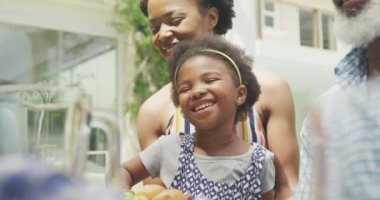 Mutlu Afro-Amerikan ailesi konuşuyor ve bahçede kahvaltı yapıyor. Aile birlikte dışarıda vakit geçiriyor..