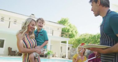 Kafkasyalı mutlu bir aile bahçede barbekü yapıp yemek yiyor. Aile evde birlikte vakit geçiriyor..