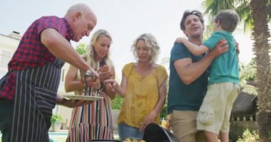 Kafkasyalı mutlu bir aile bahçede barbekü yapıp yemek yiyor. Aile evde birlikte vakit geçiriyor..