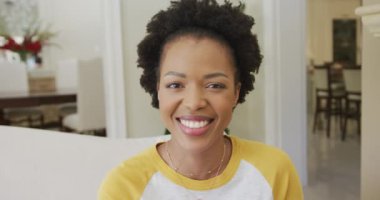 Oturma odasında kameraya bakan gülümseyen Afrikalı Amerikalı kadının portresi. Evde yalnız zaman geçirmek..