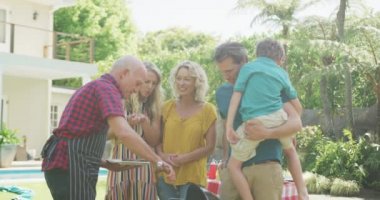 Kafkasyalı mutlu bir aile bahçede barbekü yapıp yemek yiyor. Aile evde birlikte vakit geçiriyor..