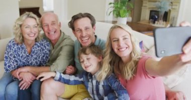 Kafkasyalı mutlu bir aile selfie çekip oturma odasında oturuyor. Aile evde birlikte vakit geçiriyor..