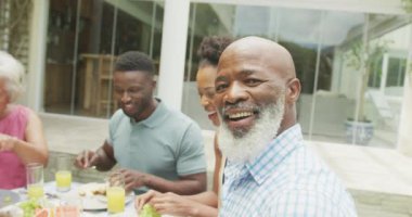 Mutlu Afro-Amerikan ailesinin portresi bahçede konuşuyor ve kahvaltı yapıyor. Aile birlikte dışarıda vakit geçiriyor..