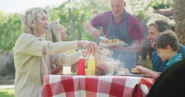 Happy caucasian family having barbecue and talking in garden. family spending time together at home.