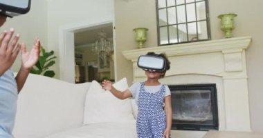 Mutlu Afro-Amerikan kızları oturma odasında vr kulaklık kullanıyor. Aile evde birlikte vakit geçiriyor..