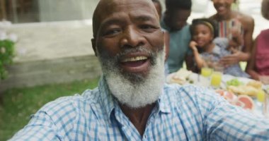 Mutlu Afro-Amerikan aile portresi. Selfie çekip bahçede kahvaltı yapıyorlar. Aile birlikte dışarıda vakit geçiriyor..