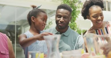 Mutlu Afro-Amerikan ailesi konuşuyor ve bahçede kahvaltı yapıyor. Aile birlikte dışarıda vakit geçiriyor..