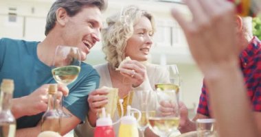 Kafkasyalı mutlu bir aile yemek yiyor ve bahçede şarap içiyor. Aile evde birlikte vakit geçiriyor..