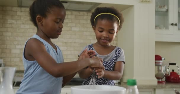 2人のアフリカ系アメリカ人の女の子が台所で材料を焼くと混合します 家族で家で過ごす時間は — ストック動画