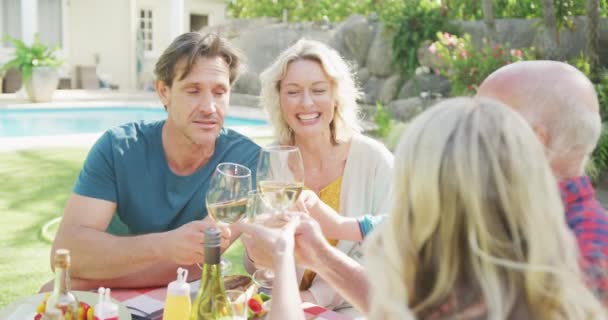 Ευτυχισμένη Οικογένεια Καυκάσιων Που Τρώει Και Πίνει Κρασί Στον Κήπο — Αρχείο Βίντεο