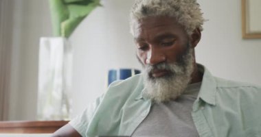 Üzgün Afrikalı Amerikalı son sınıf öğrencisinin yalnız oturduğu bir video. Emeklilik yaşam tarzı, ev konseptinde dijital olarak oluşturulmuş video ile zaman geçirme.