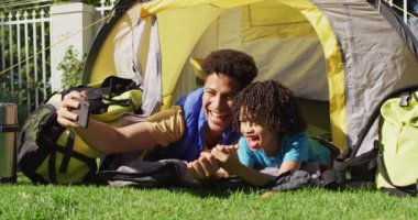 Mutlu çift ırklı adam ve oğlu bahçede akıllı telefon kullanarak selfie çekiyorlar. ev hayatı, evde zaman geçirmek..