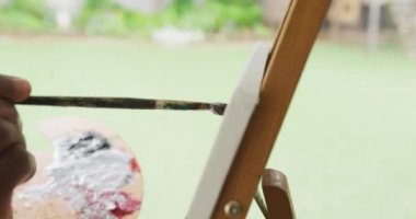 Afro-Amerikan son sınıf öğrencisinin dışarıda resim çizerken çekilmiş videosu. Emeklilik yaşam tarzı, ev konseptinde dijital olarak oluşturulmuş video ile zaman geçirme.