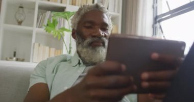 Afro-Amerikan son sınıf öğrencisinin tablet kullandığı bir video. Emeklilik yaşam tarzı, ev konseptinde dijital olarak oluşturulmuş video ile zaman geçirme.
