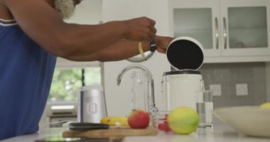 Afrika asıllı Amerikalı son sınıf öğrencisinin smoothie hazırlarken videosu. Emeklilik yaşam tarzı, ev konseptinde dijital olarak oluşturulmuş video ile zaman geçirme.