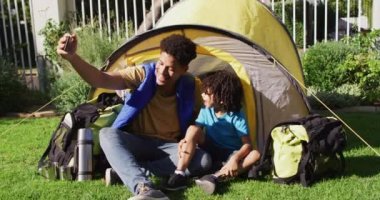 Mutlu çift ırklı adam ve oğlu bahçede akıllı telefon kullanarak selfie çekiyorlar. ev hayatı, evde zaman geçirmek..