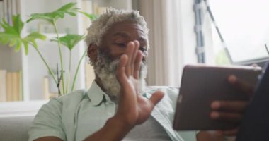 Afro-Amerikan son sınıf öğrencisinin tablet kullandığı bir video. Emeklilik yaşam tarzı, ev konseptinde dijital olarak oluşturulmuş video ile zaman geçirme.