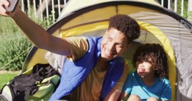 Mutlu çift ırklı adam ve oğlu bahçede akıllı telefon kullanarak selfie çekiyorlar. ev hayatı, evde zaman geçirmek..