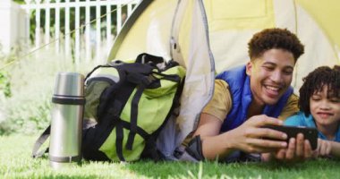 Mutlu melez adam ve oğlu bahçede akıllı telefon kullanıyor. ev hayatı, evde zaman geçirmek..