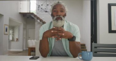 Afro-Amerikan son sınıf öğrencisinin kahve içerkenki mutlu videosu. Emeklilik yaşam tarzı, ev konseptinde dijital olarak oluşturulmuş video ile zaman geçirme.