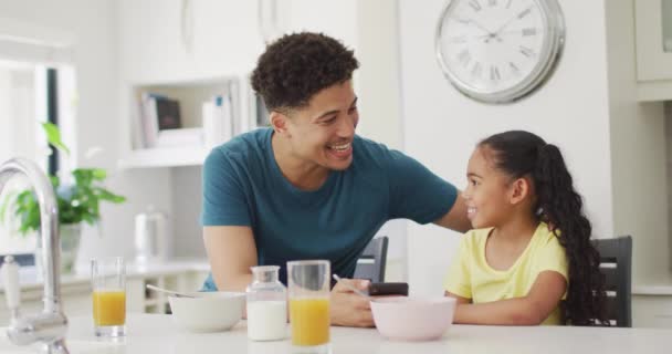 幸せな出産の父と娘が一緒に朝食を食べ スマートフォンを使用しています 国内での生活や家での自由時間 — ストック動画