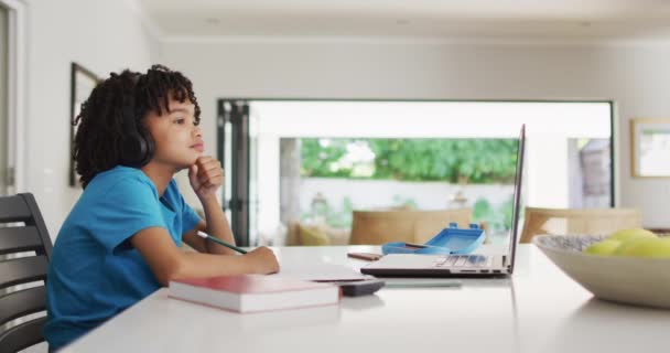 Happy Biracial Αγόρι Κάθεται Στο Τραπέζι Χρησιμοποιώντας Φορητό Υπολογιστή Και — Αρχείο Βίντεο