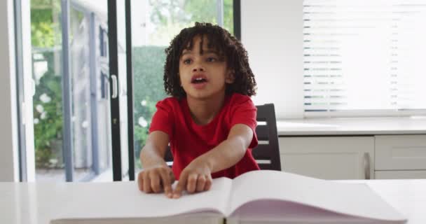 Χαρούμενο Παιδί Που Κάθεται Στο Τραπέζι Στην Κουζίνα Και Διαβάζει — Αρχείο Βίντεο