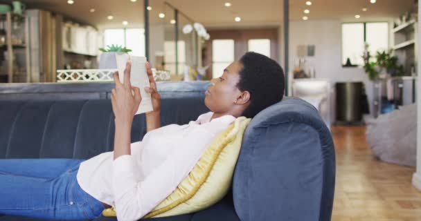 Mujer Afroamericana Feliz Tumbada Sofá Sala Estar Libro Lectura Vida — Vídeos de Stock