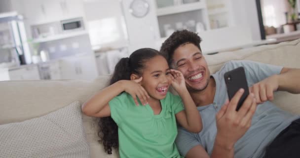 Feliz Padre Biracial Hija Sentados Sofá Usando Teléfono Inteligente Estilo — Vídeos de Stock
