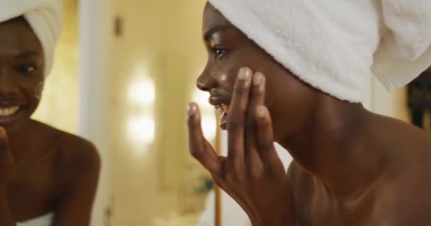 Χαμογελώντας Αφροαμερικανή Γυναίκα Πετσέτα Κοιτάει Στον Καθρέφτη Και Χρησιμοποιεί Κρέμα — Αρχείο Βίντεο