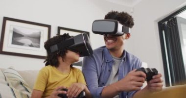 Çift ırklı adam ve oğlu video oyunu oynarken video kulaklık takıyorlar. ev hayatı, evde zaman geçirmek..