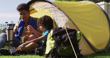 Mutlu melez adam ve oğlu bahçedeki termostan su içiyorlar. ev hayatı, evde zaman geçirmek..