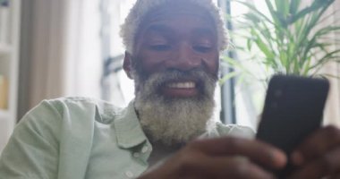 Akıllı telefon kullanan Afrikalı son sınıf öğrencisinin videosu. Emeklilik yaşam tarzı, ev konseptinde dijital olarak oluşturulmuş video ile zaman geçirme.
