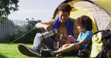 Mutlu melez adam ve oğlu bahçedeki termostan su içiyorlar. ev hayatı, evde zaman geçirmek..