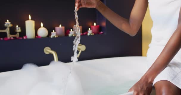 Afroamerykanka Ręcznikiem Przygotowująca Kąpiel Dotykająca Wody Łazience Koncepcja Zdrowia Urody — Wideo stockowe