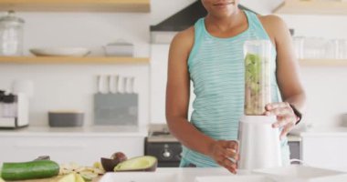 Mutlu Afro-Amerikan kadın mutfakta sağlıklı bir içecek hazırlıyor. ev hayatı, evde boş zaman geçirmek..