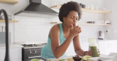 Mutlu Afro-Amerikan kadın mutfakta sağlıklı bir içecek hazırlıyor. ev hayatı, evde boş zaman geçirmek..