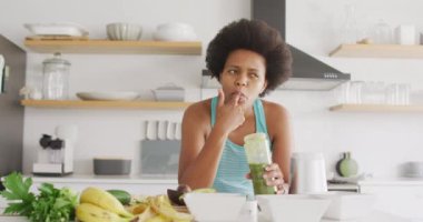 Mutlu Afro-Amerikan kadın mutfakta sağlıklı bir içecek hazırlıyor. ev hayatı, evde boş zaman geçirmek..