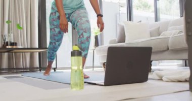 Mutlu Afro-Amerikan spor giyer, egzersiz yapar, dizüstü bilgisayar kullanır. ev hayatı, evde boş zaman geçirmek..