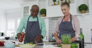 Mavi önlük giyip mutfakta yemek pişiren kıdemli bir çift. Evde birlikte vakit geçirmek..