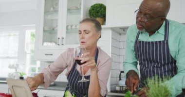 Mavi önlük giyip mutfakta şarap içen kıdemli bir çift. Evde birlikte vakit geçirmek..