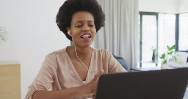 Mutlu Afro-Amerikan kadın masada dizüstü bilgisayar kullanarak oturuyor. ev hayatı, evde boş zaman geçirmek..