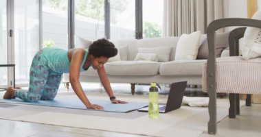 Mutlu Afro-Amerikan spor giyer, egzersiz yapar, dizüstü bilgisayar kullanır. ev hayatı, evde boş zaman geçirmek..
