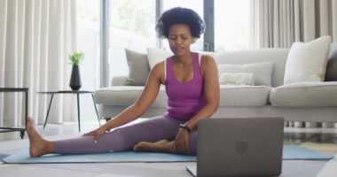 Mutlu Afro-Amerikan spor giyer, egzersiz yapar, dizüstü bilgisayar kullanır. ev hayatı, evde boş zaman geçirmek..