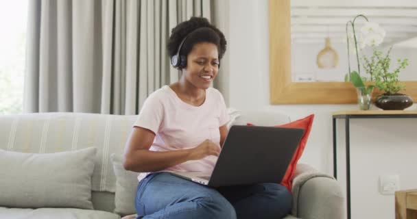 Happy African American Woman Memakai Headphone Duduk Sofa Menggunakan Laptop — Stok Video