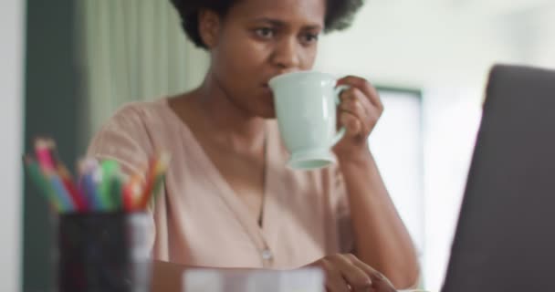 Χαρούμενη Αφροαμερικανή Που Κάθεται Στο Τραπέζι Λάπτοπ Και Πίνει Καφέ — Αρχείο Βίντεο