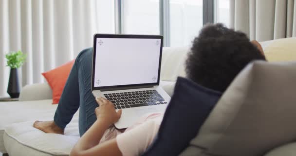 コピースペースのラップトップを使用して ソファに座って幸せなアフリカ系アメリカ人女性 国内での生活や家での自由時間 — ストック動画