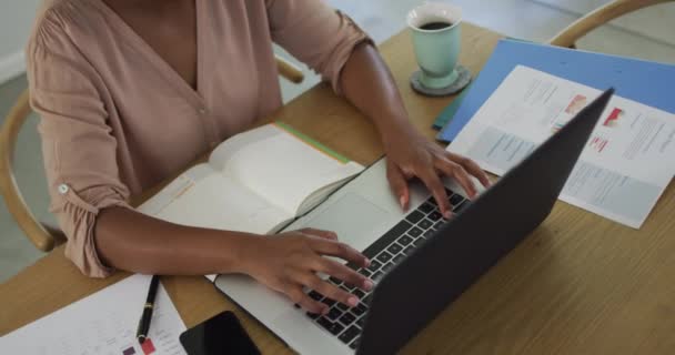 幸せなアフリカ系アメリカ人女性がノートパソコンを使ってテーブルに座っている 国内での生活や家での自由時間 — ストック動画